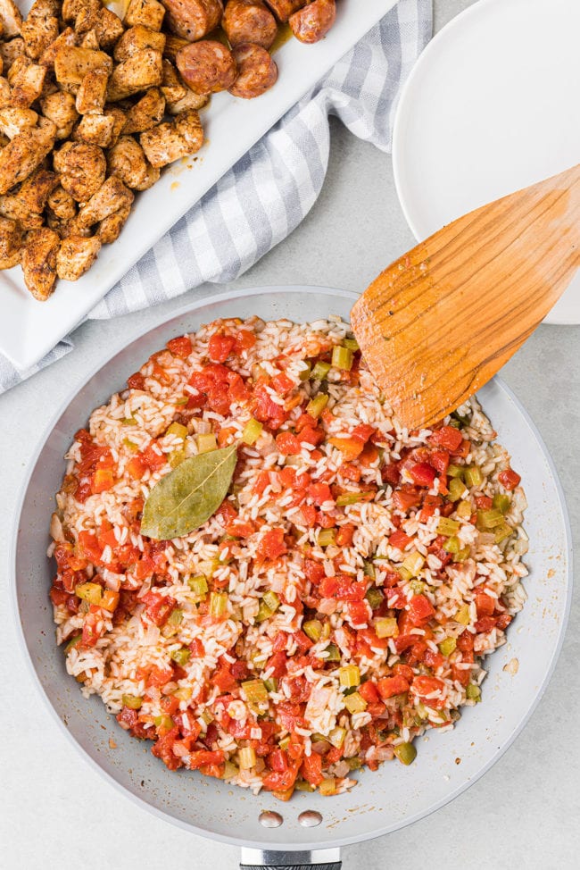 homemade jambalaya in a skillet with a wooden spatula to stir with