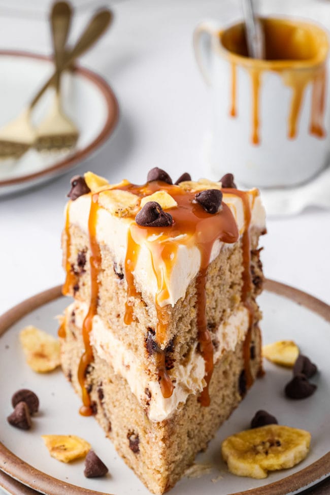 slice of banana layer cake with caramel sauce dripping over the sides