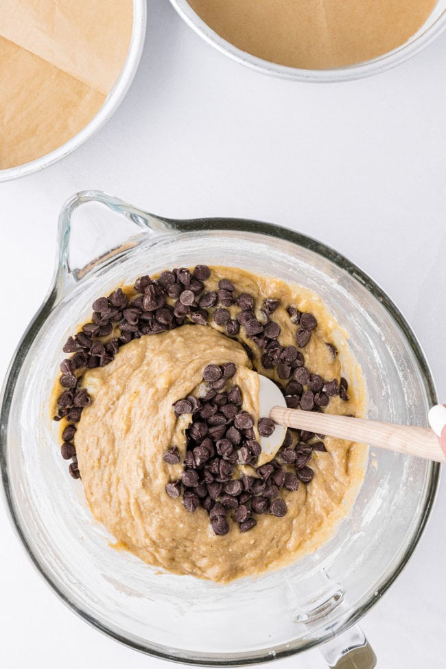 banana cake batter and chocolate chips in a glass mixing bowl