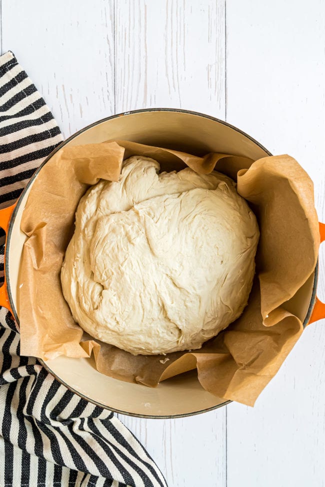 bread dough in a dutch oven lined with parchment paper