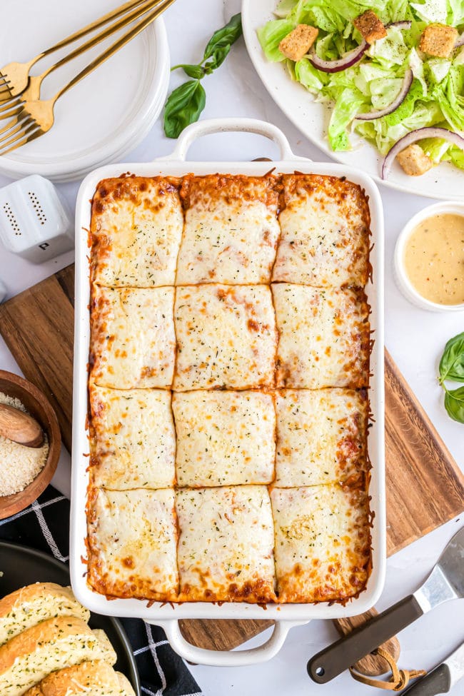 a white baking dish with beef lasagna with ricotta cut into servings
