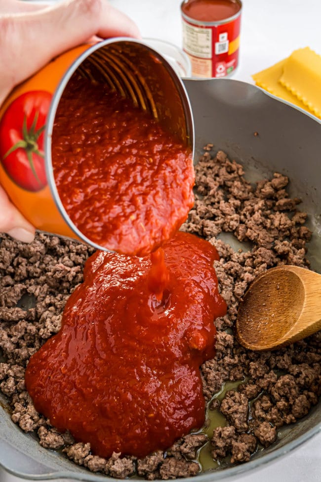 adding crushed tomatoes to browned ground beef