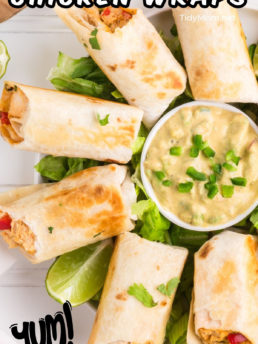 firecracker chicken wraps on a white platter with a bowl of avocado sauce in the center