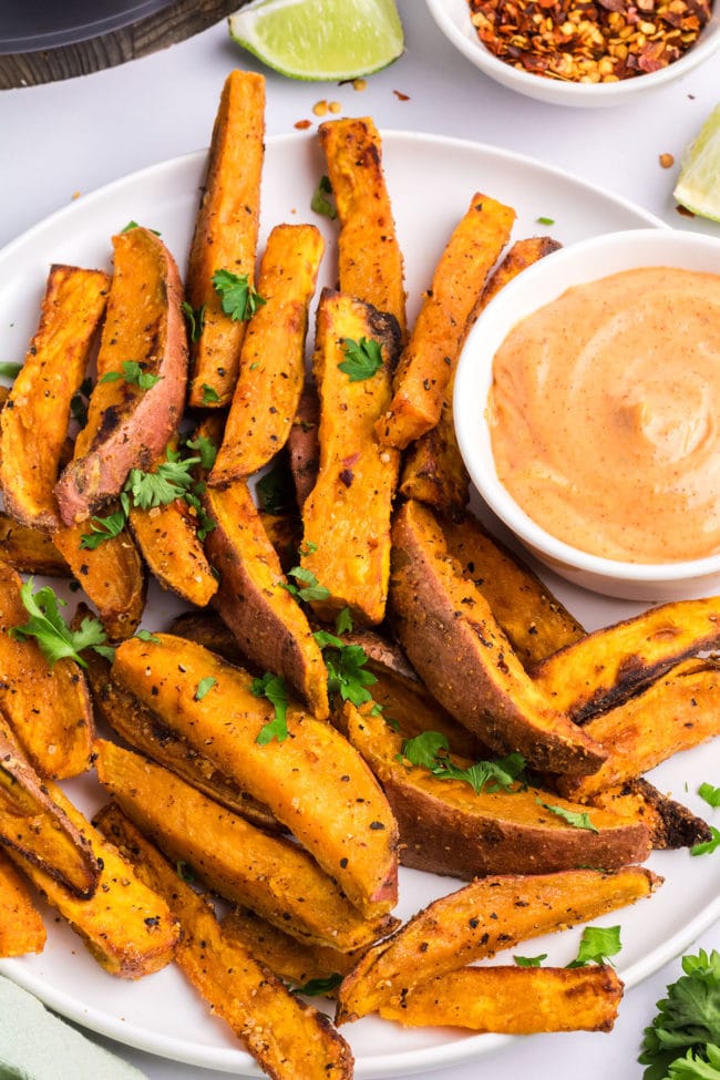 Air Fryer Crispy sweet potato wedges on a platter with zesty mayo sauce.