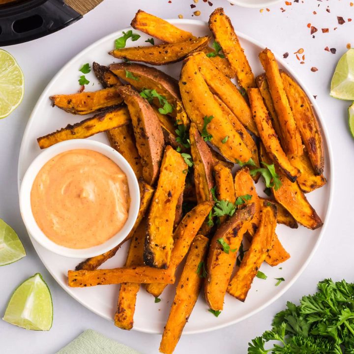 Air Fryer Crispy sweet potato wedges on a platter with zesty mayo dipping sauce.