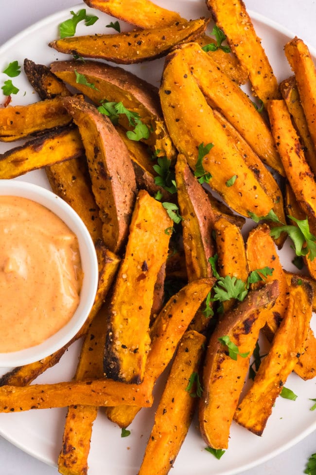 Air Fryer Crispy sweet potato wedges on a platter with spicy mayo sauce.