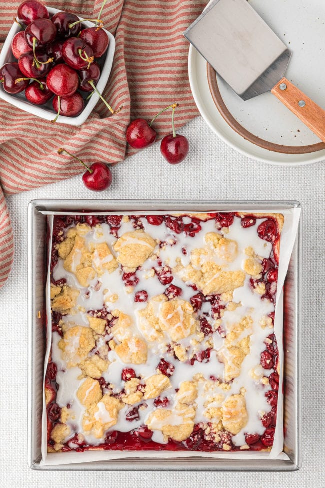 cherry pie bars with an almond glaze in a baking pan