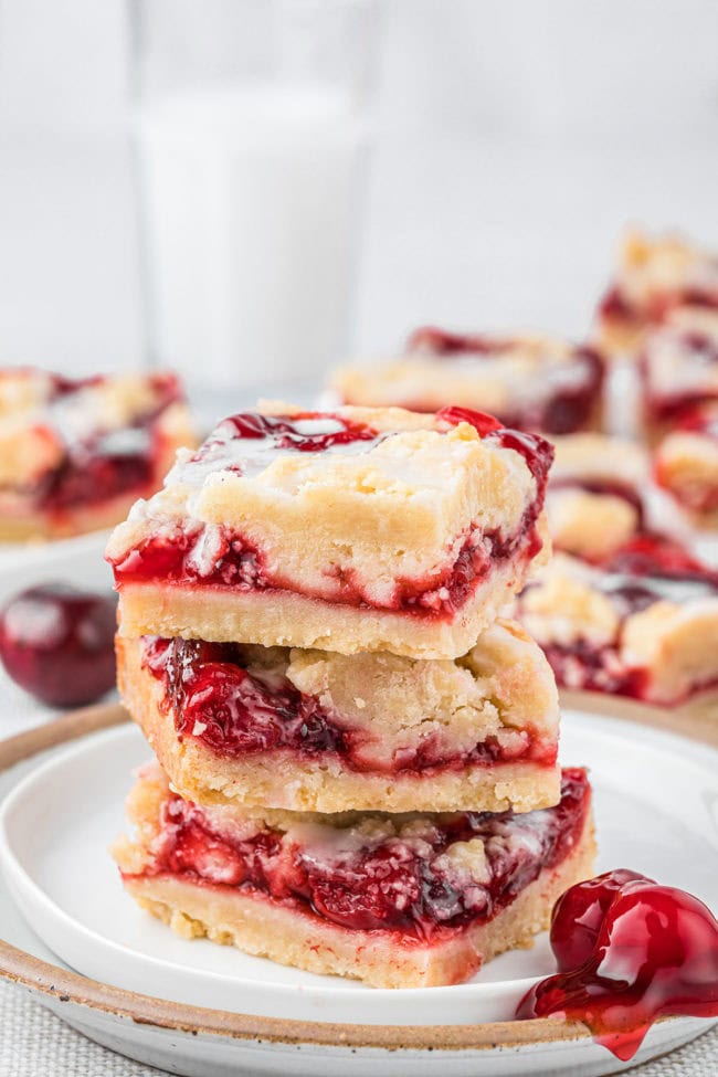 Three cherry pie bars in a stack on a plate