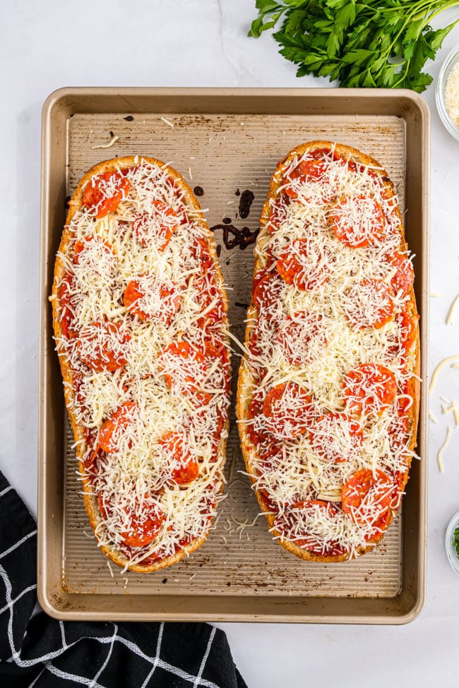 loaf of bread sliced open topped with cheese and pepperoni