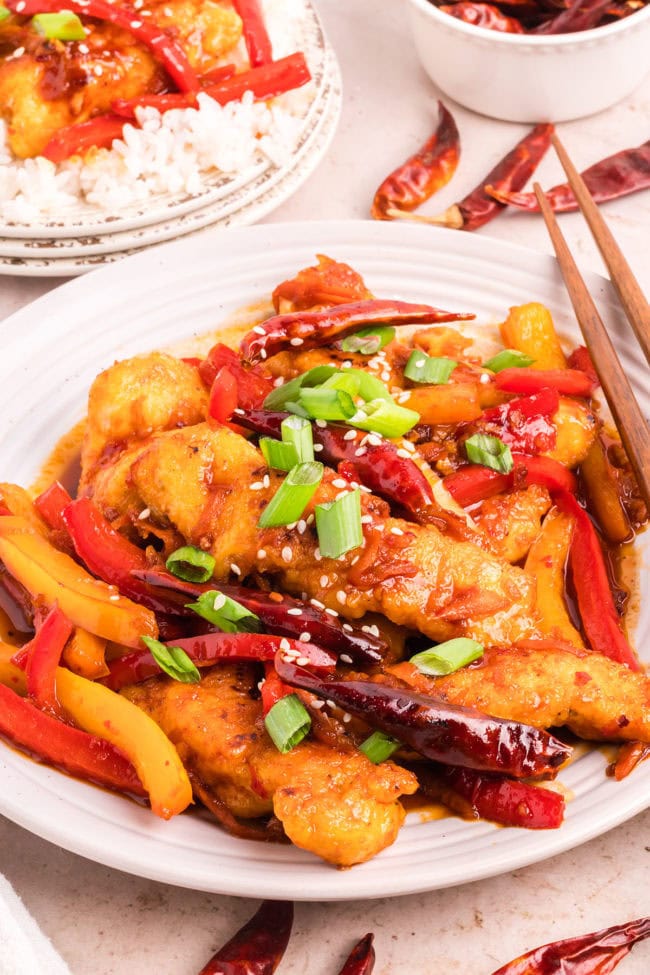 hot and spicy chicken with colorful veggies on a plate with chopsticks