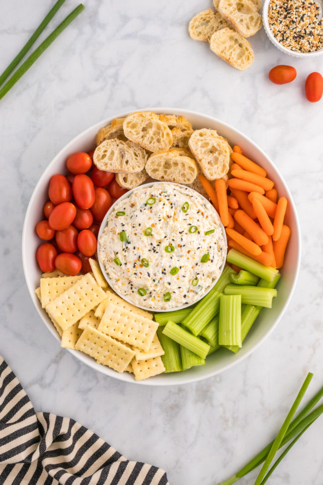 veggies and crackers a round a bowl of everything but the bagel dip