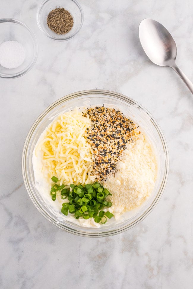 mixing everything bagel dip in a glass bowl