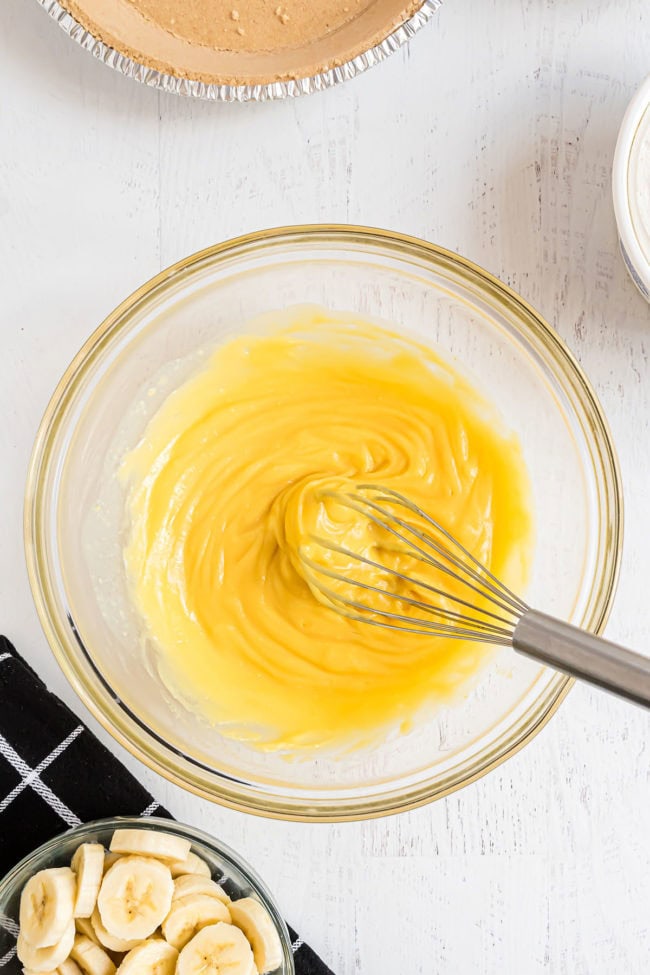 whisking vanilla pudding in a glass mixing bowl