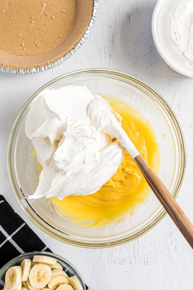 folding CoolWhip into pudding in a glass mixing bowl