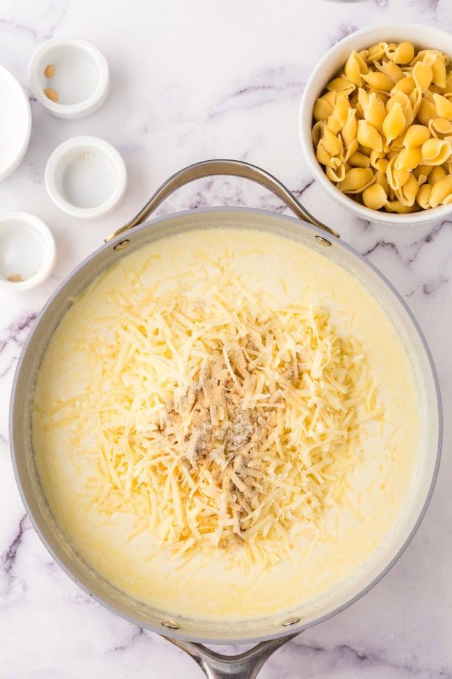 making a creamy white mac and cheese sauce in a skillet