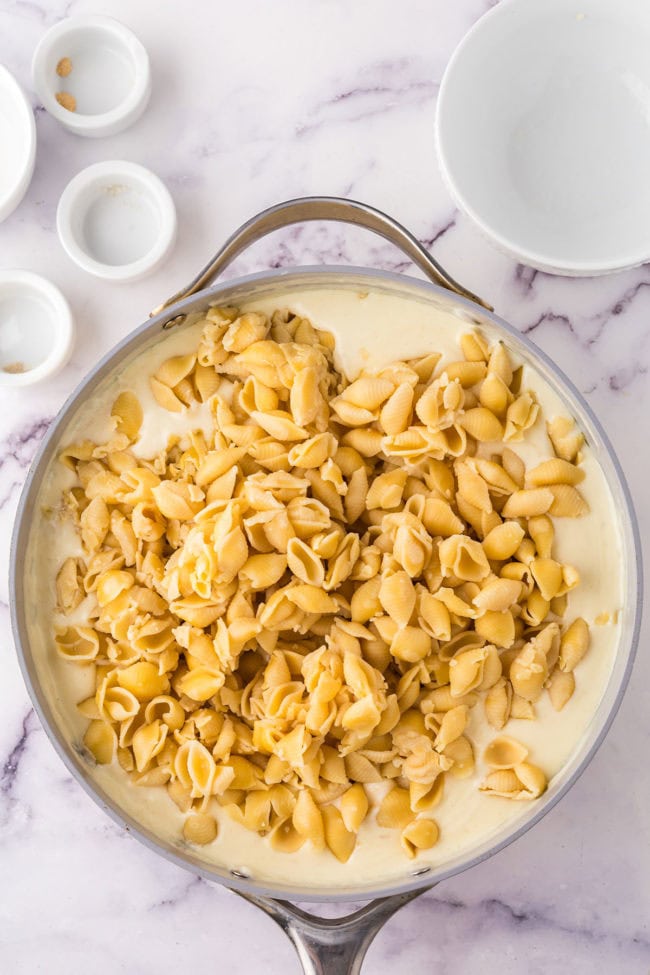 Adding cooked pasta to a creamy cheese sauce
