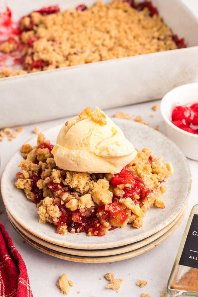 A plated serving of sweet cherry crumble with a scoop of vanilla ice cream 