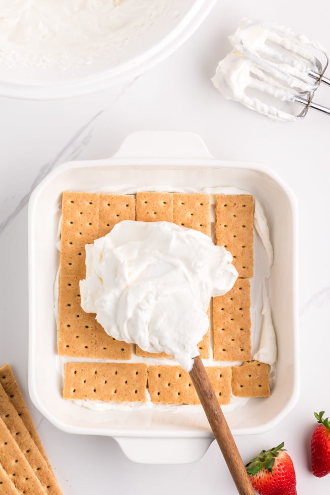 adding a layer of whipped cream to an icebox cake