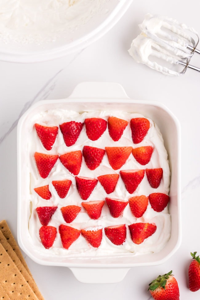 adding fresh strawberries to an icebox cake