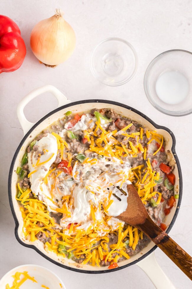 mixing casserole ingredients in a white cast iron skillet