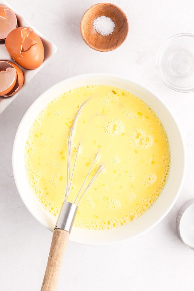 scrambled eggs mixture in a bowl with a wire whisk