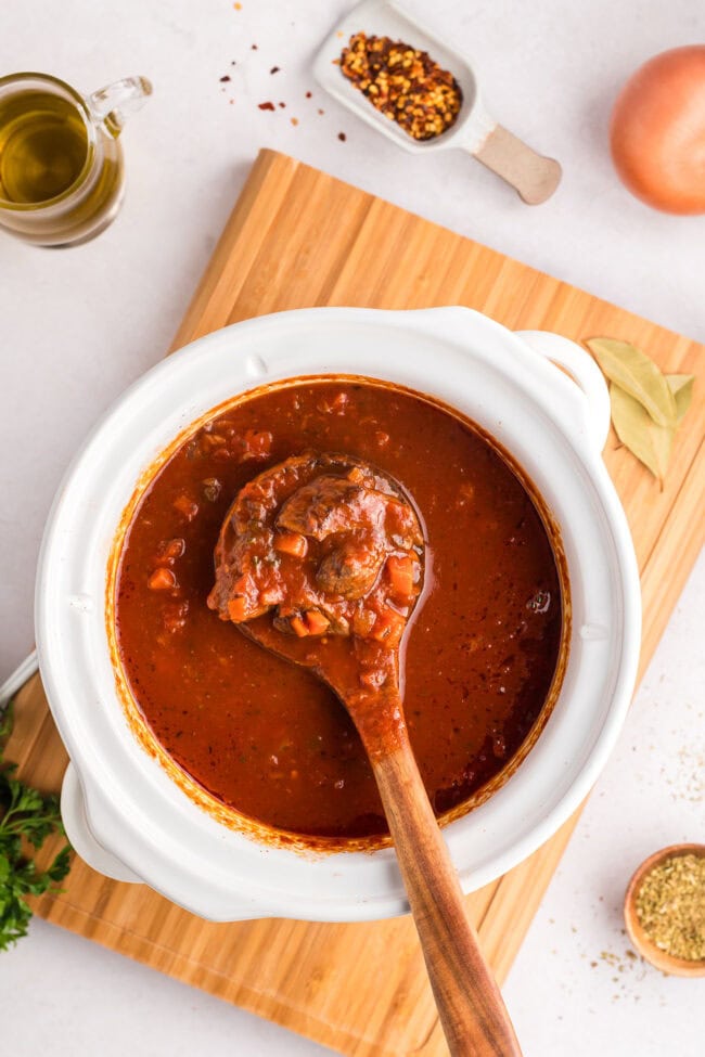 ragu in a white crockpot with a wooden spoon