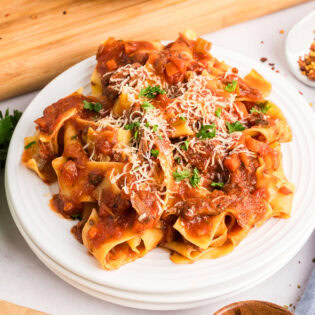 slow cooker beef ragu over pasta on a white plate