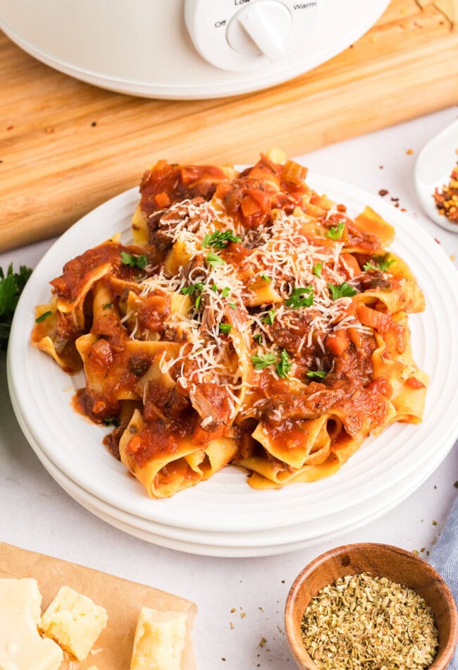 slow cooker beef ragu over pasta on a white plate