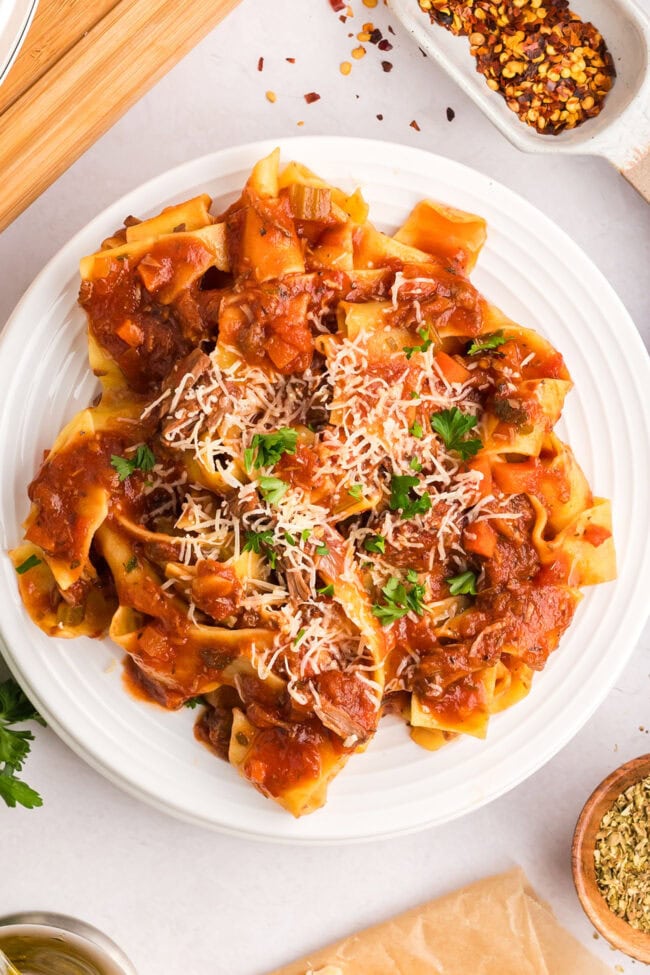 beef ragu over pappardelle pasta on a white plate