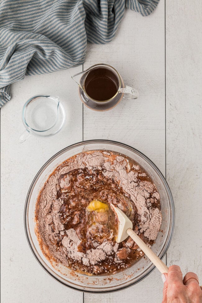 mixing chocolate cake wet ingredients in a clear mixing bowl.