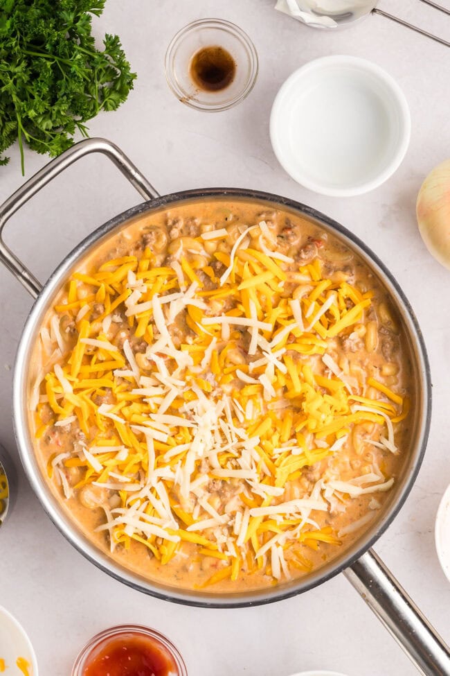 making cheesy hamburger casserole in a deep skillet