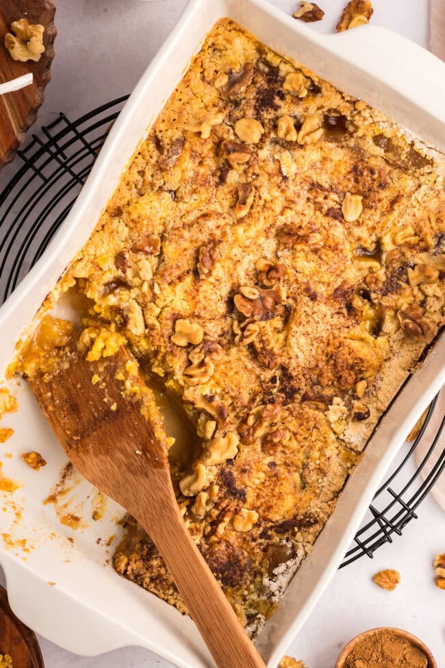 baked caramel apple dump cake with a wooden spoon in a baking dish