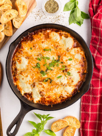 Lasagna Dip in cast iron skillet with a red towel