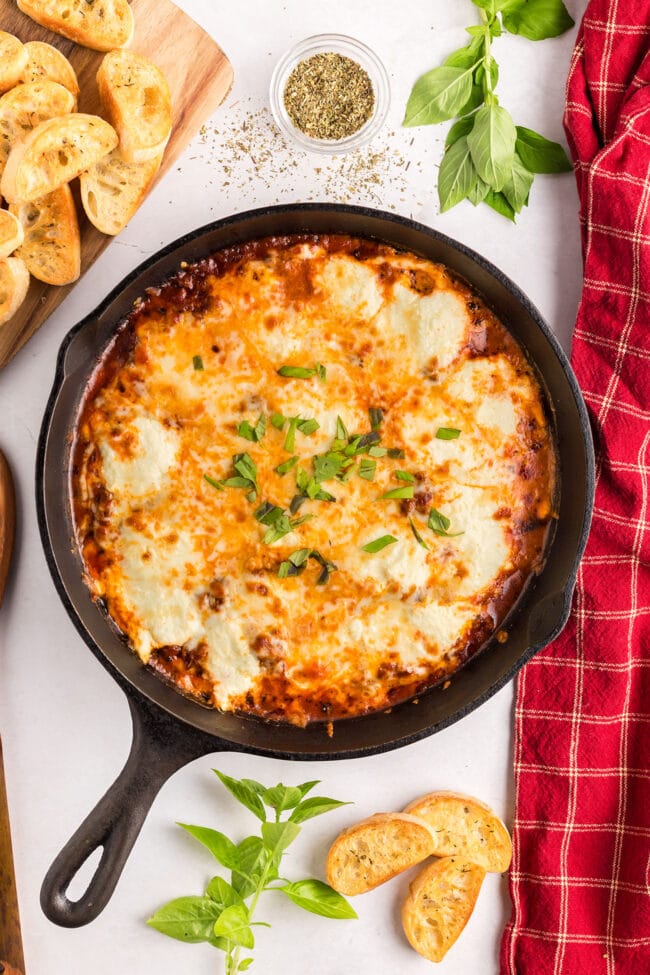 Lasagna Dip in cast iron skillet with a red towel