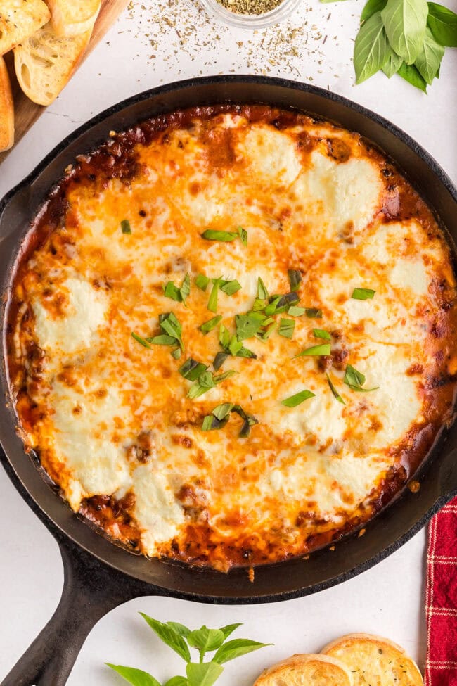 Lasagna Dip garnished with fresh basil in a cast iron skillet