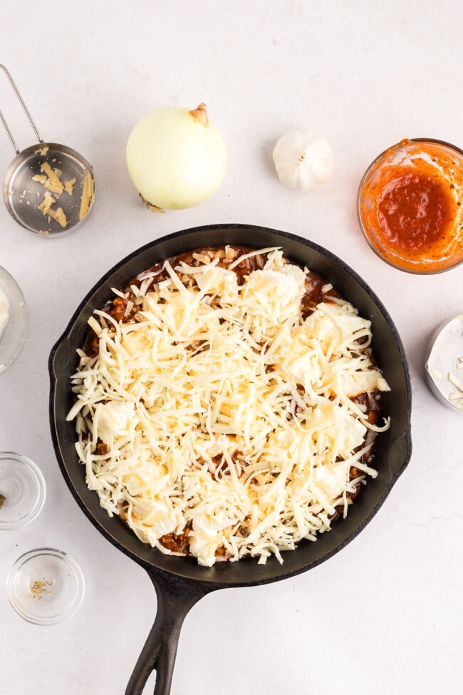 Lasagna Dip with cheese ready for the oven in a cast iron skillet