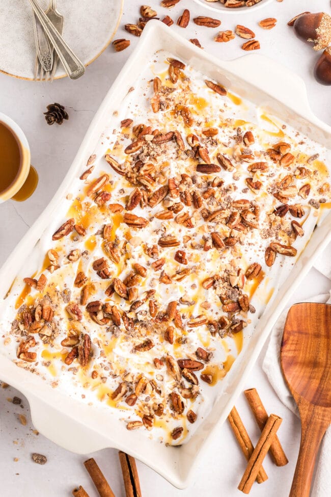 fall cake in a white dish with caramel sauce, pecans and toffee pieces on top