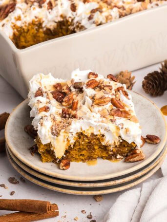 serving of Pumpkin Spice Poke Cake With Caramel Sauce on a stack of small plate