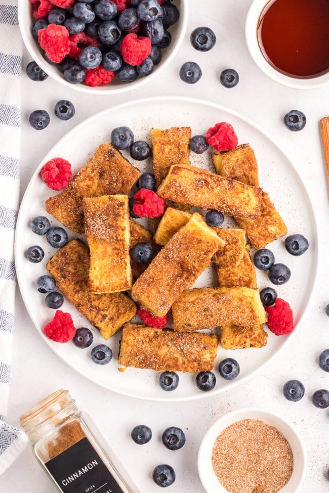 plate of cinnamon sugar french toast sticks with fresh berries and syrup