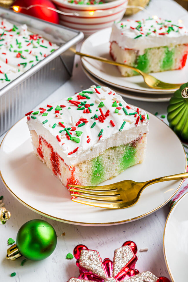 slice of Christmas poke cake on a plate with a gold fork