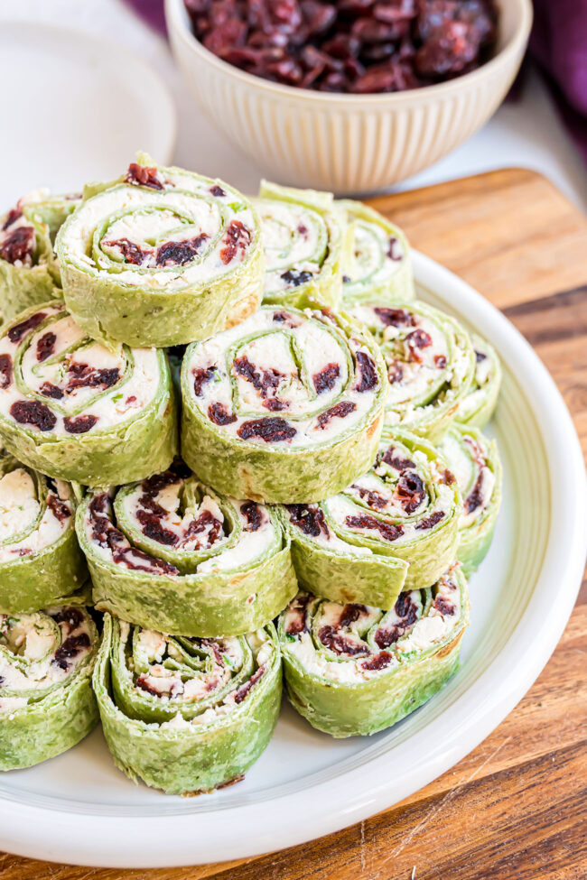 a plate stacked with cranberry feta pinwheels with green tortillas for the holidays