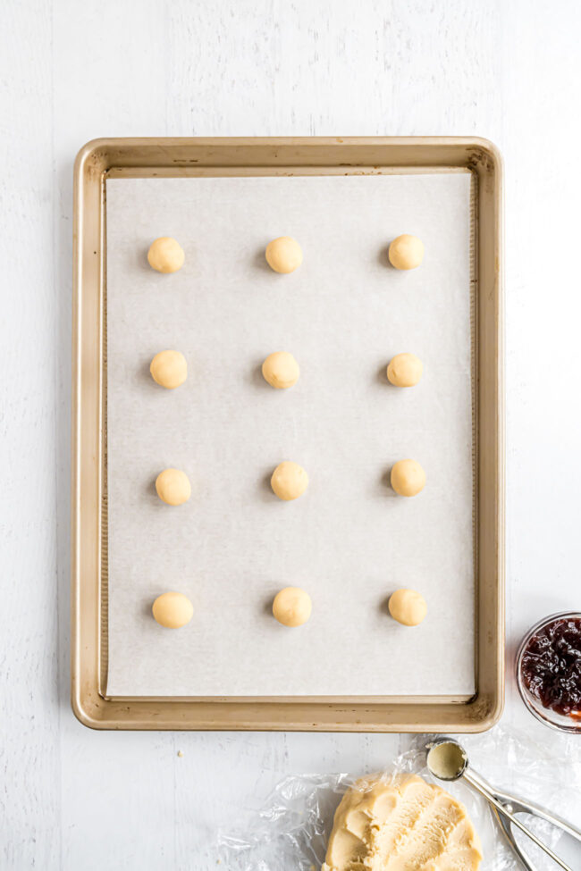 cookie dough rolled into balls on a sheet pan