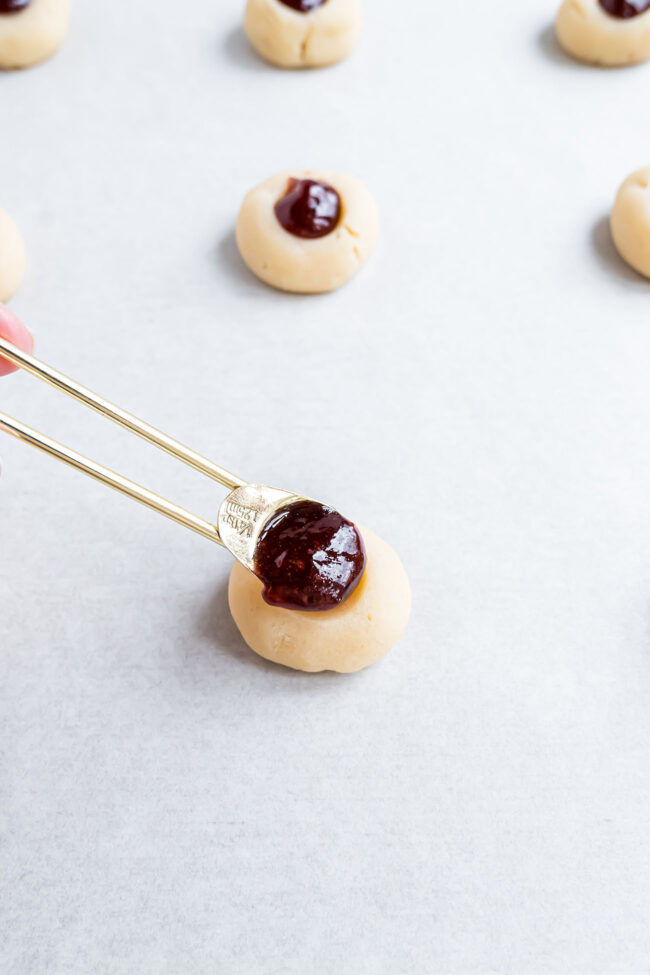 adding jam to balls of cookie dough