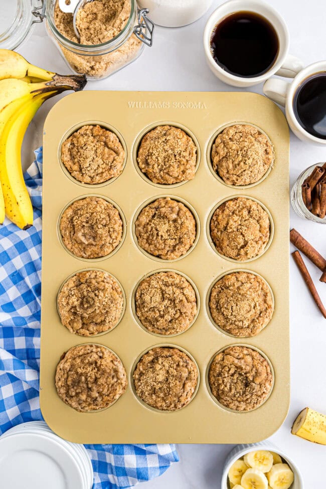 baked banana crumb muffins in a gold muffin tin