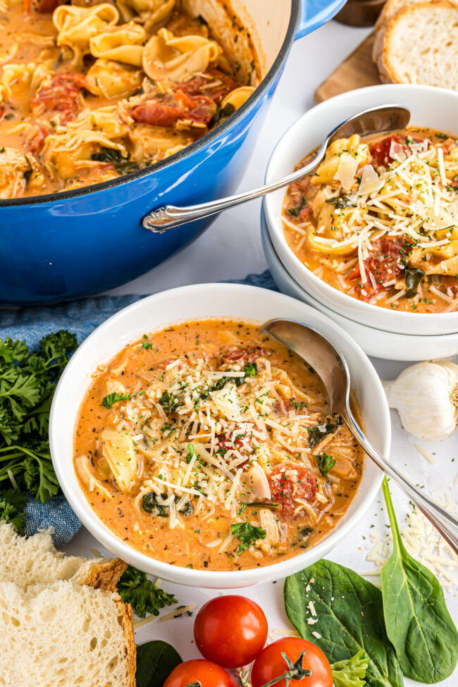 Cheese Tortellini Soup in white bowls and blue pot.