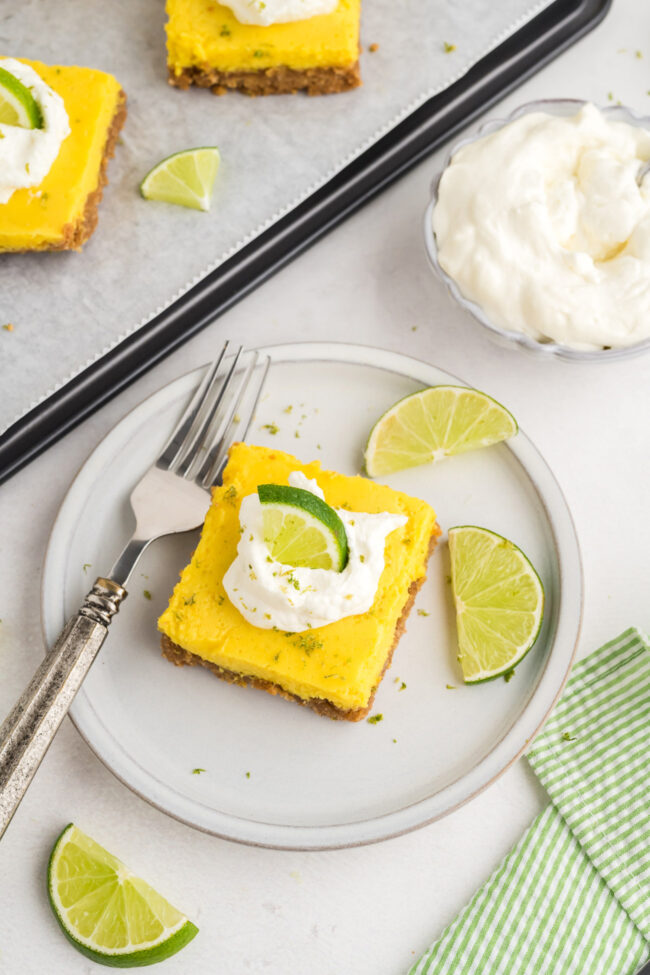 slice of key lime pie bars on a plate with a fork and whipped topping