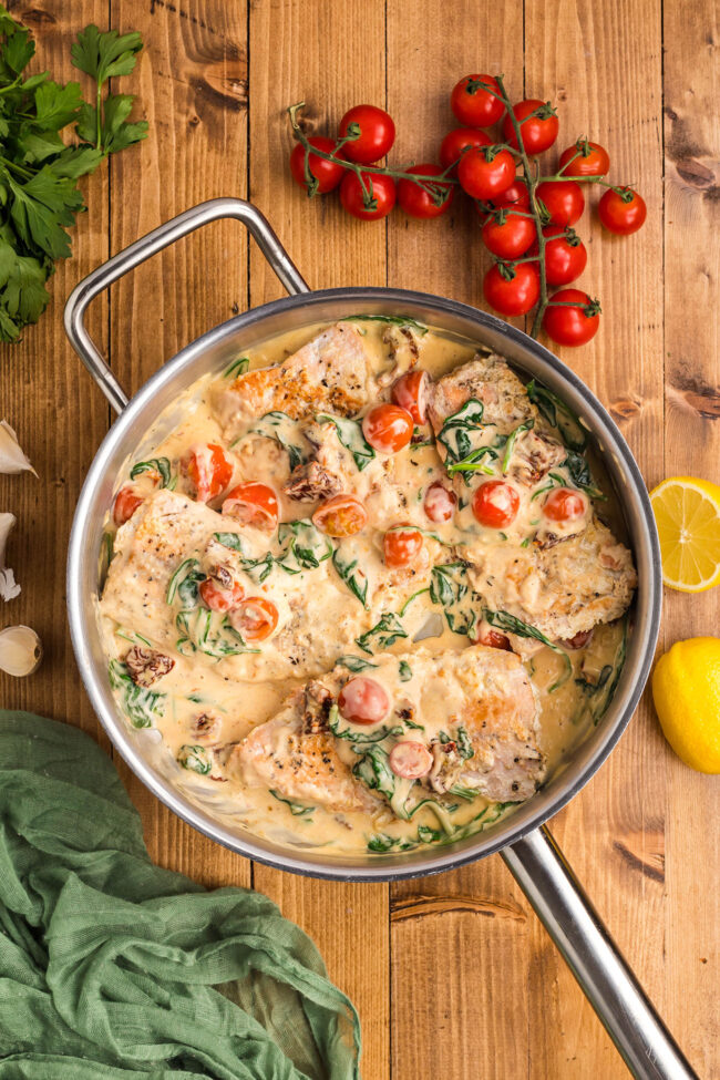 creamy tuscan salmon in a skillet with cherry tomatoes