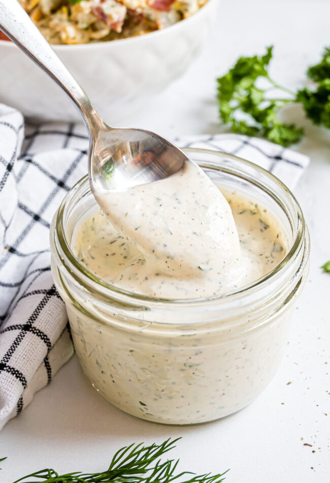 spoon dipping into a jar of homemade ranch dressing