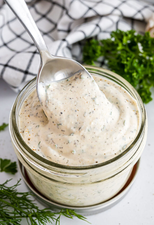spoon dipping into a jar filled with ranch dressing