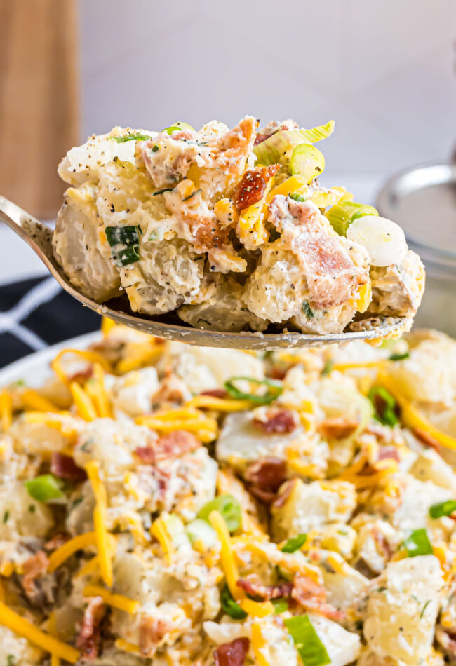 A large serving spoon with Loaded Baked Potato Salad